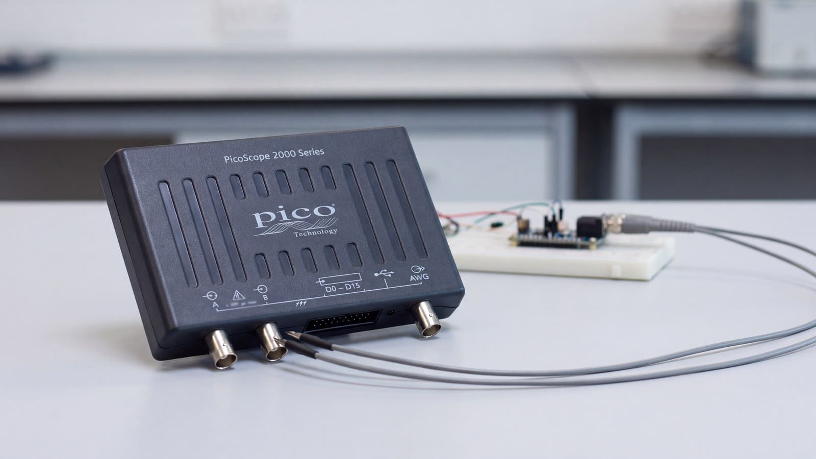 Máy hiện sóng USB nhỏ gọn PicoScope 2000 đặt trên bàn sửa chữa, que đo nối vào kênh A và B để đo mạch nguồn trên bo mạch