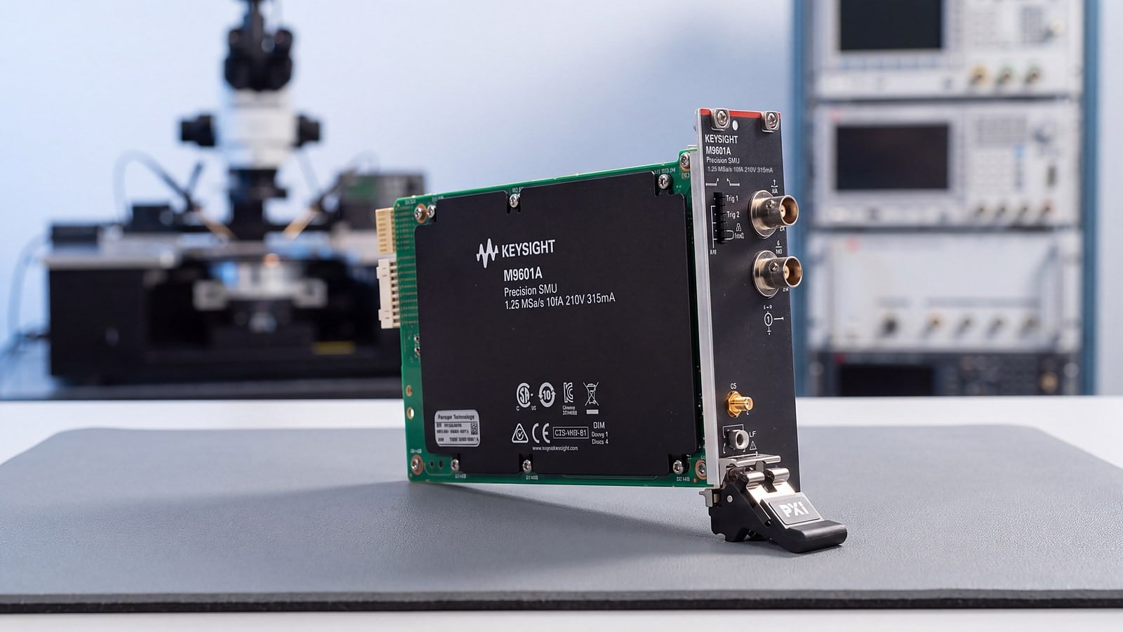 SMU PXIe Keysight M9601A trên bàn đo phòng lab đặc tính hoá linh kiện bán dẫn, phía sau là trạm dò wafer