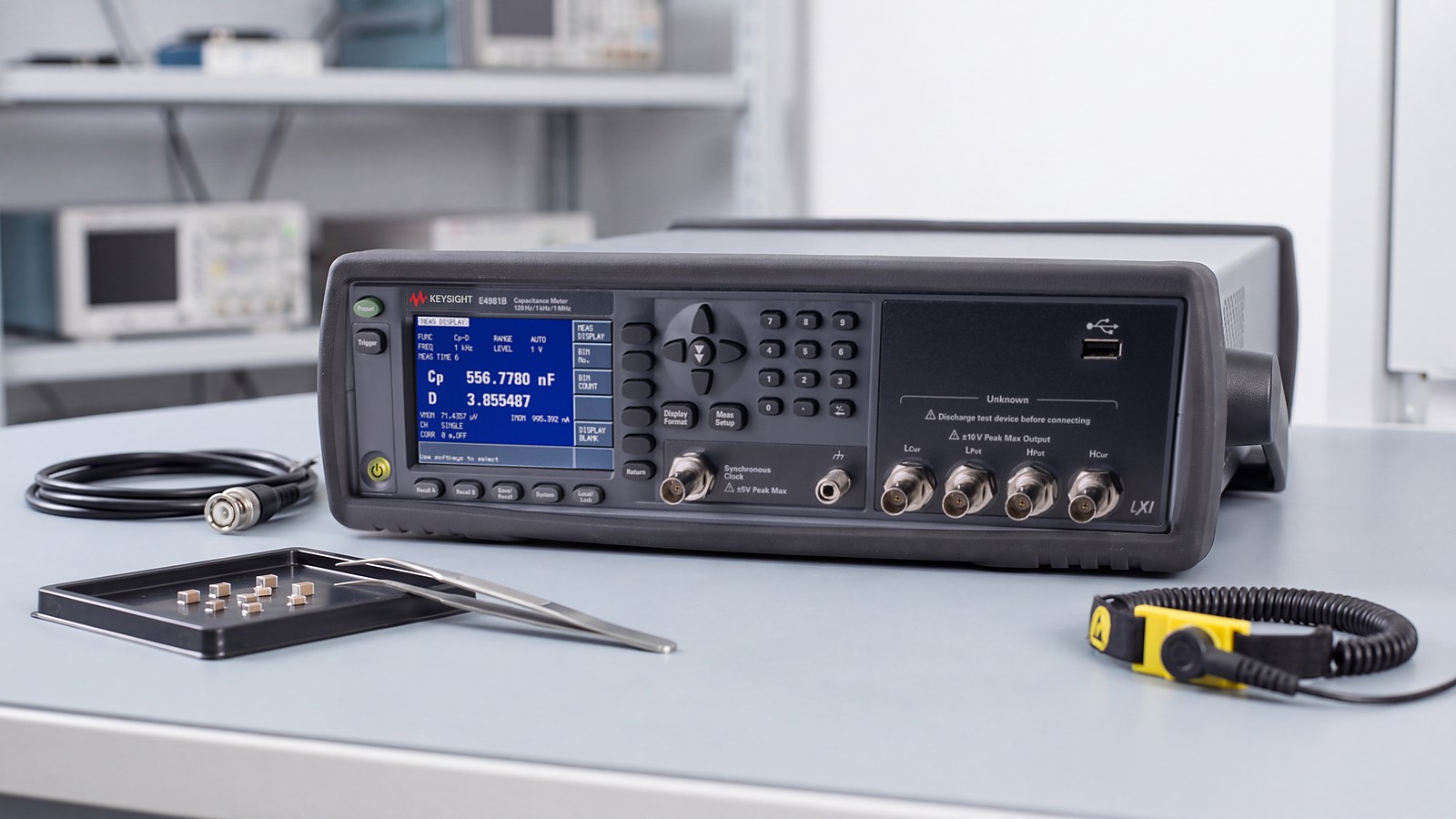 Máy đo điện dung Keysight E4981B trên bàn đo phòng QA linh kiện thụ động cạnh khay tụ gốm MLCC, nhíp gắp và cáp BNC